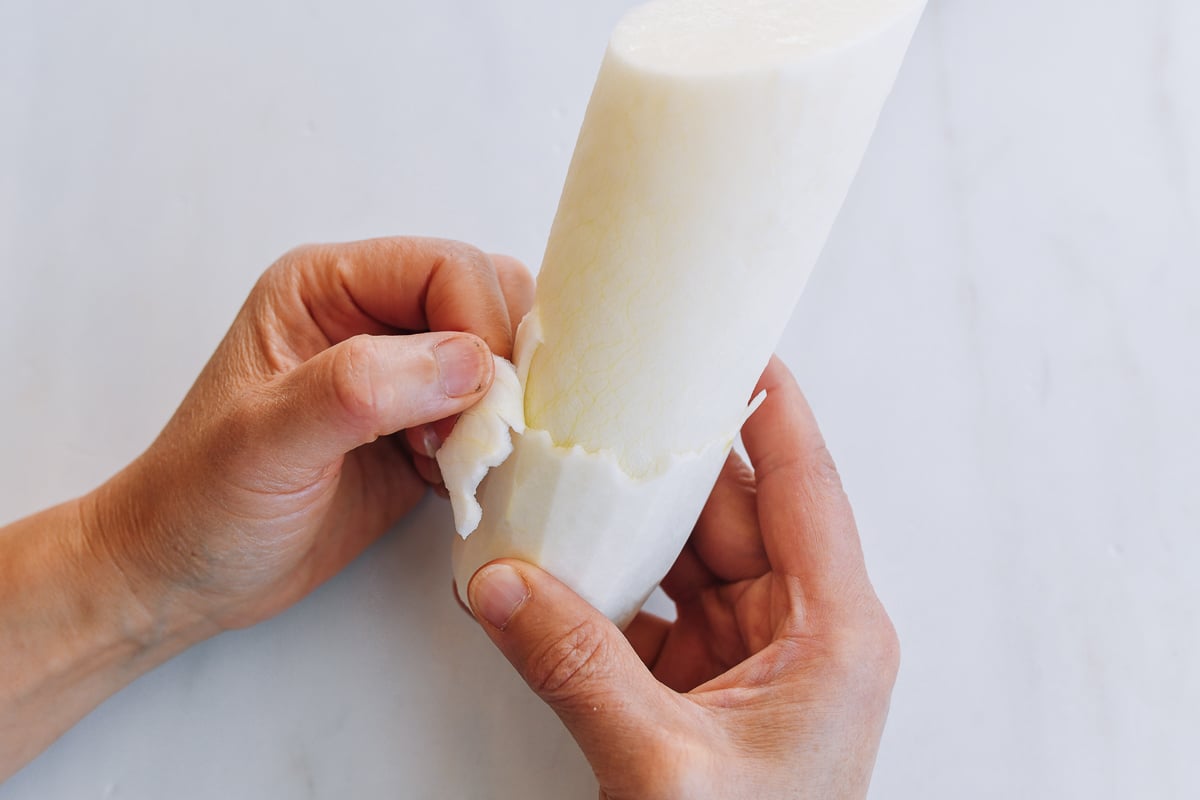 peeling bitter spicy outer layer from daikon radish