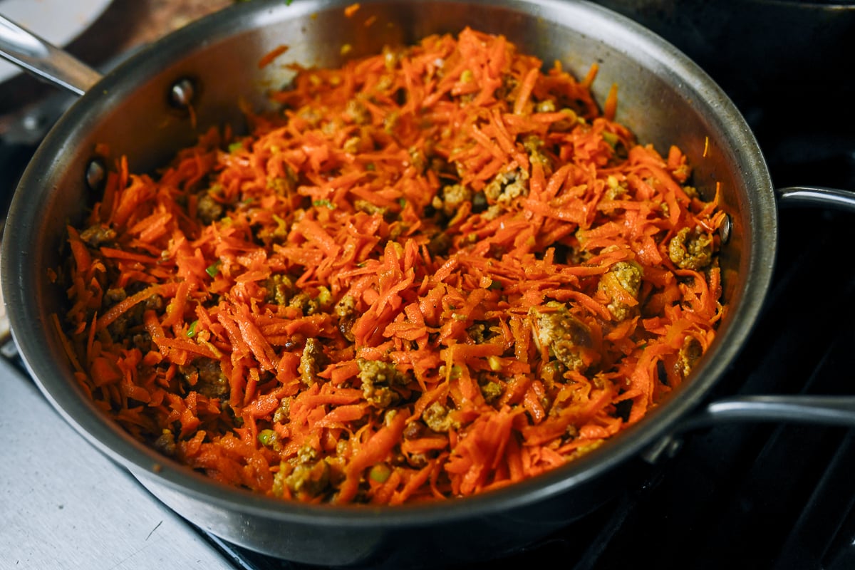 grated carrot in skillet with pork