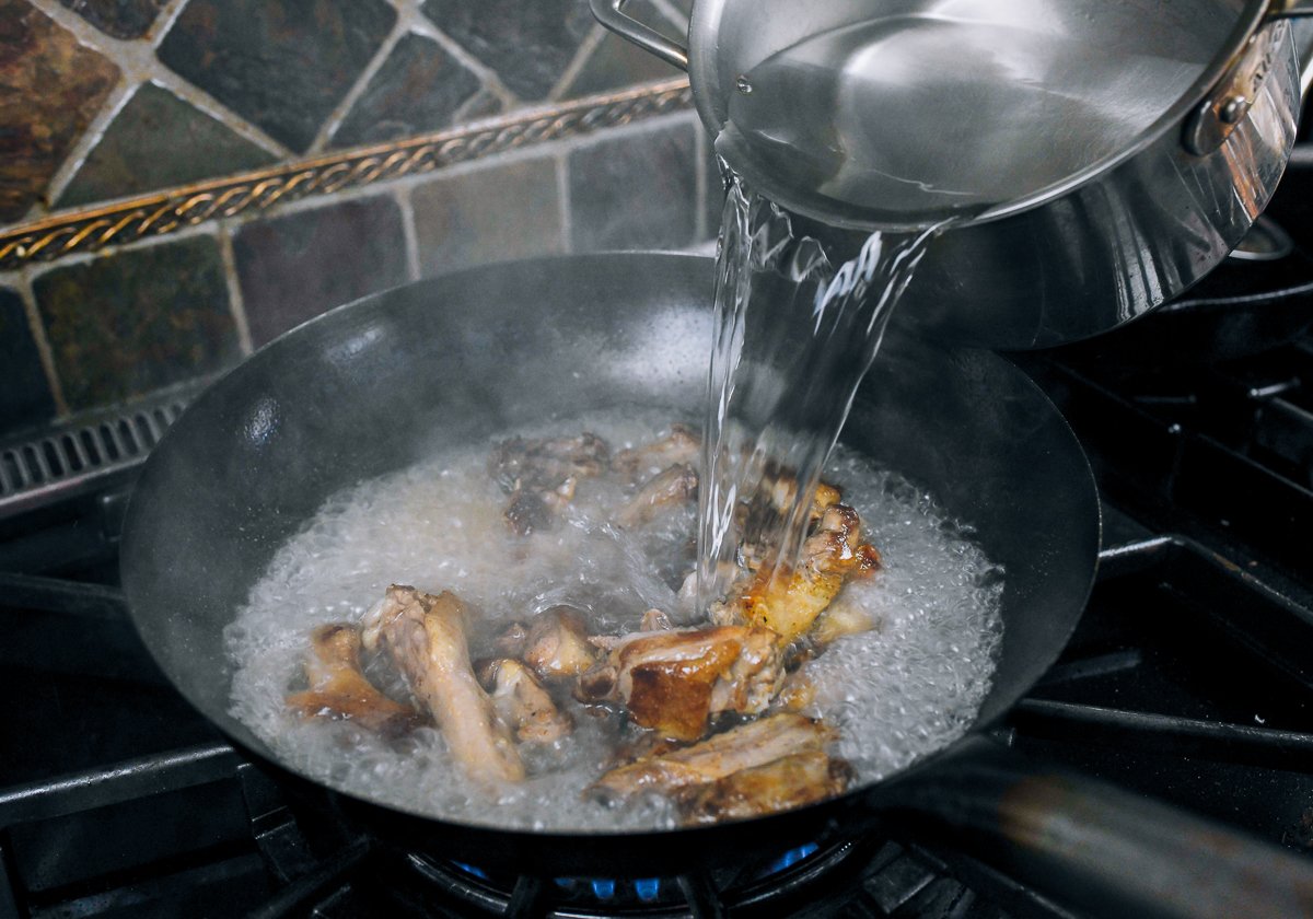 adding boiling water to pot for soup