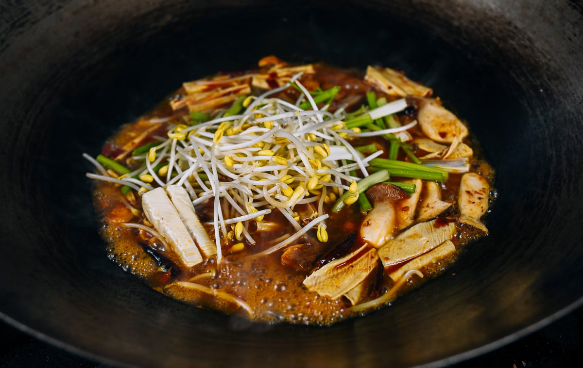 adding soybean sprouts to spicy vegetable and sauce mixture