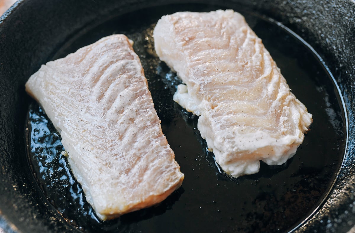 seasoned cod fillets in hot cast iron pan