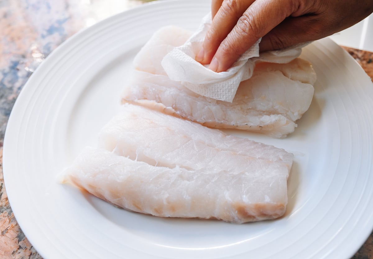patting fish fillets dry with paper towels